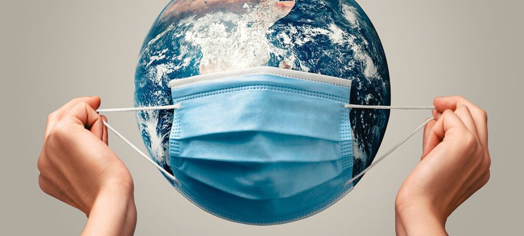 Fotografía conceptual, se observan unas manos sosteniendo un cubrebocas sobre una imagen del planeta tierra, representando una cabeza
