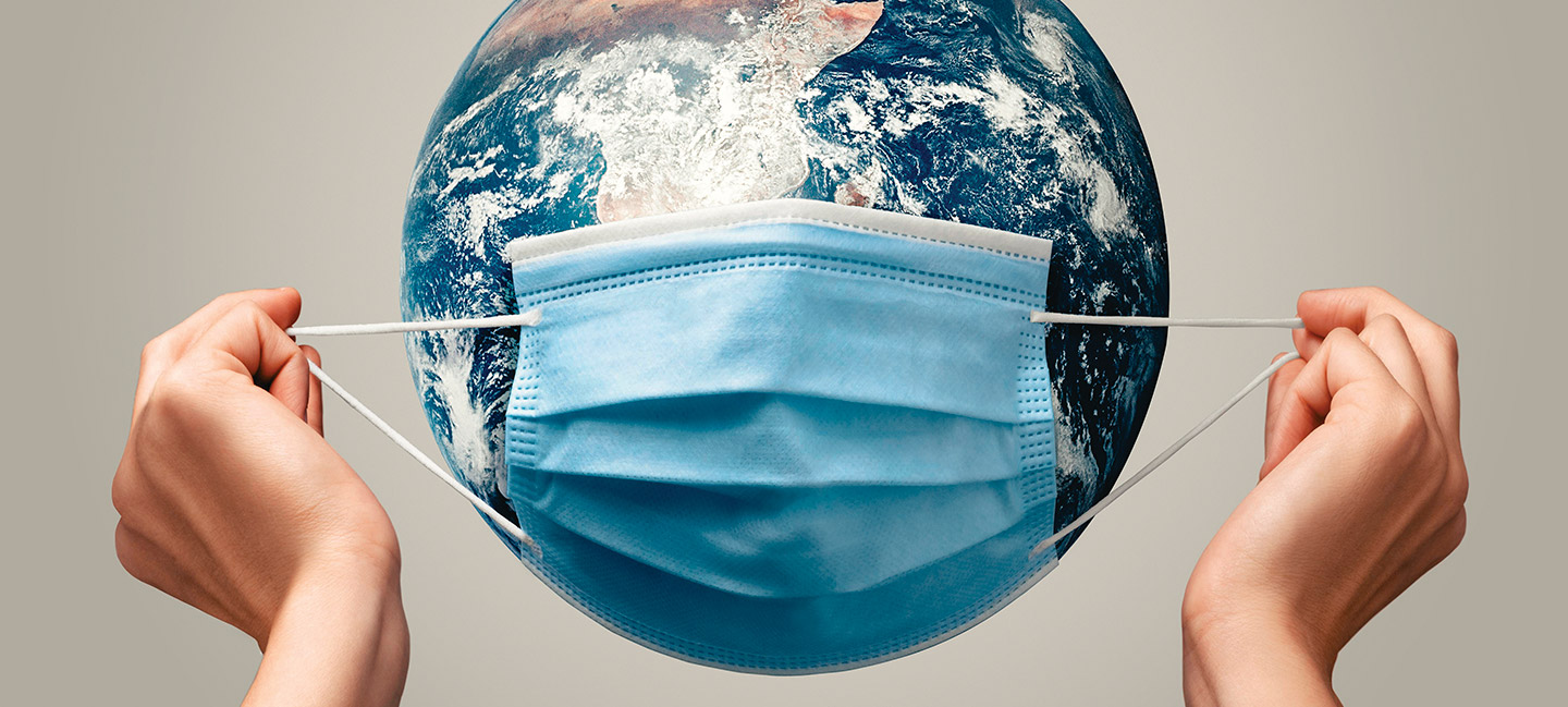 Fotografía conceptual, se observan unas manos sosteniendo un cubrebocas sobre una imagen del planeta tierra, representando una cabeza
