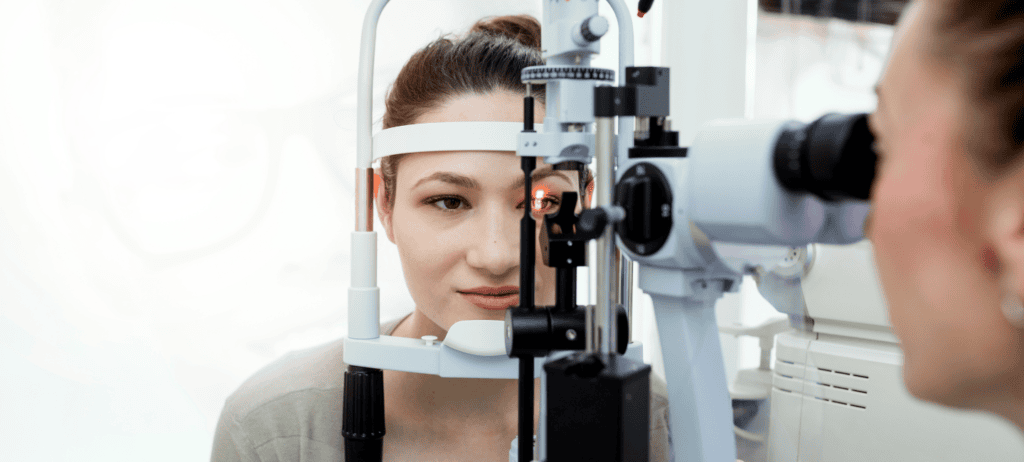 Mujer joven recibiendo examan de la vista con equipo médico de oftalmología