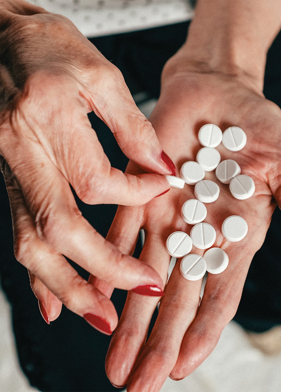 Manos de una mujer adulta mayor sosteniendo pastillas en su palma