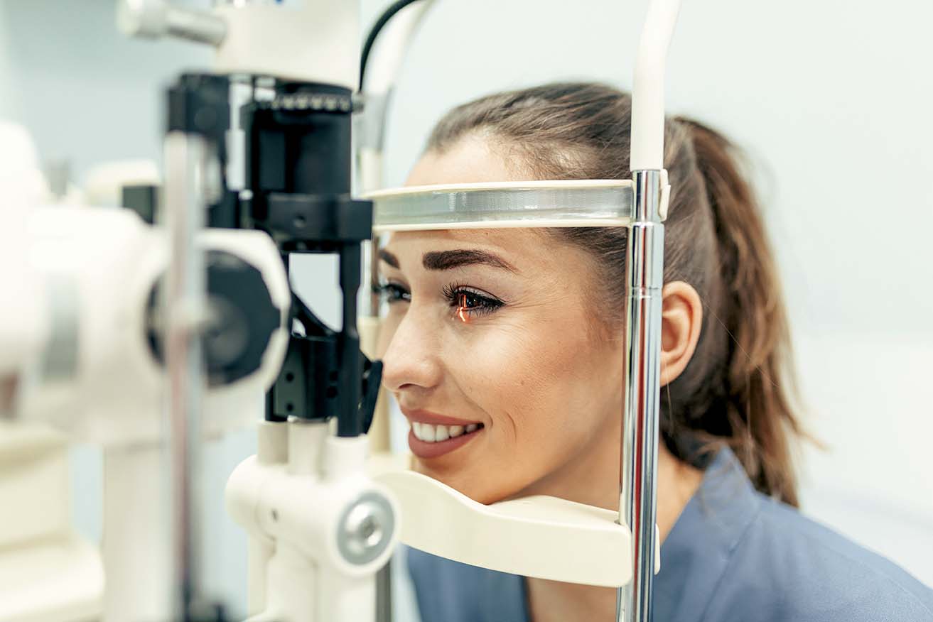 mujer joven sonriendo recibiendo examen de la vista, oftalmología