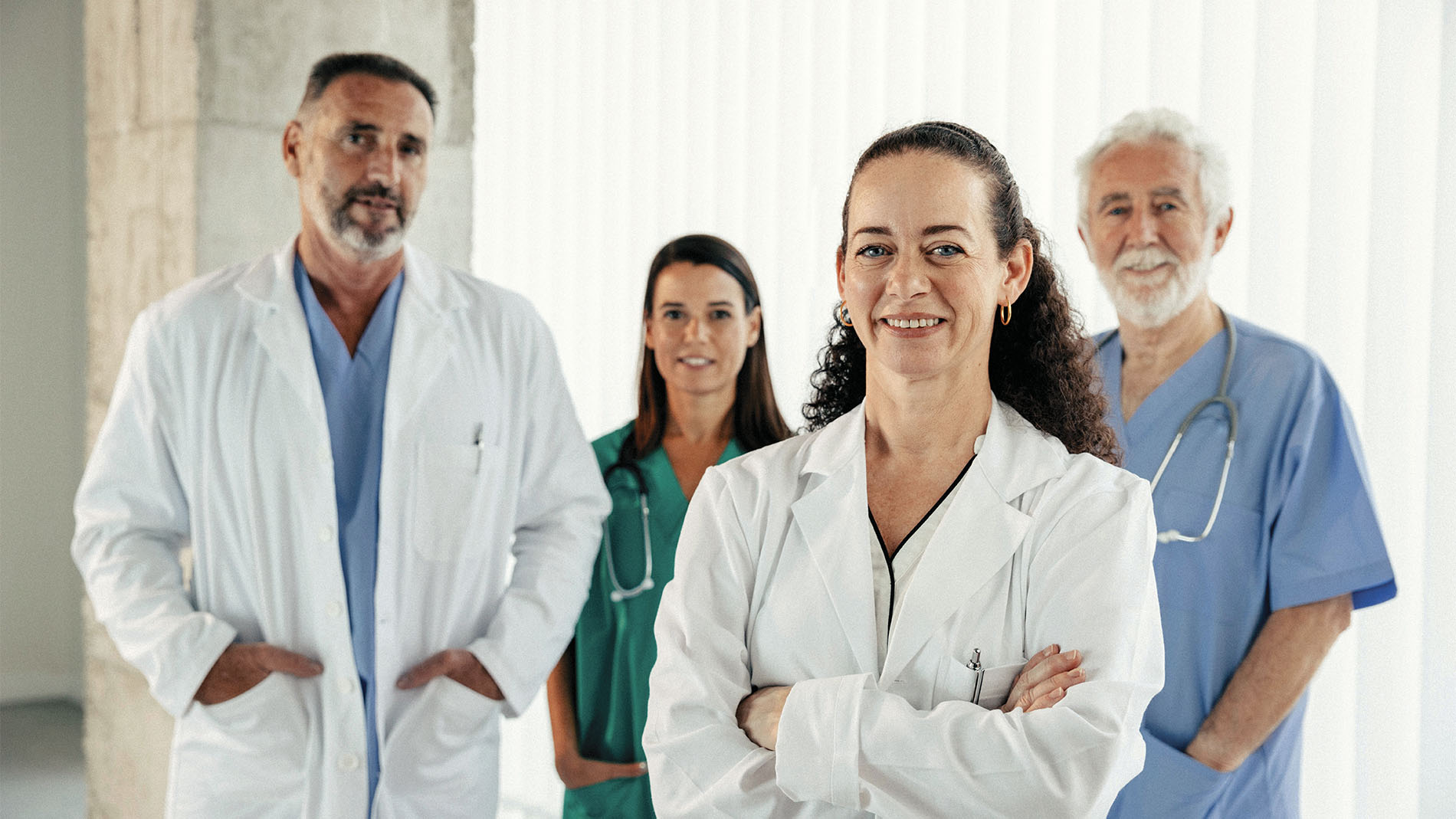 Grupo de cuatro doctores y doctoras, posando ante la cámara luciendo profesional y amigables