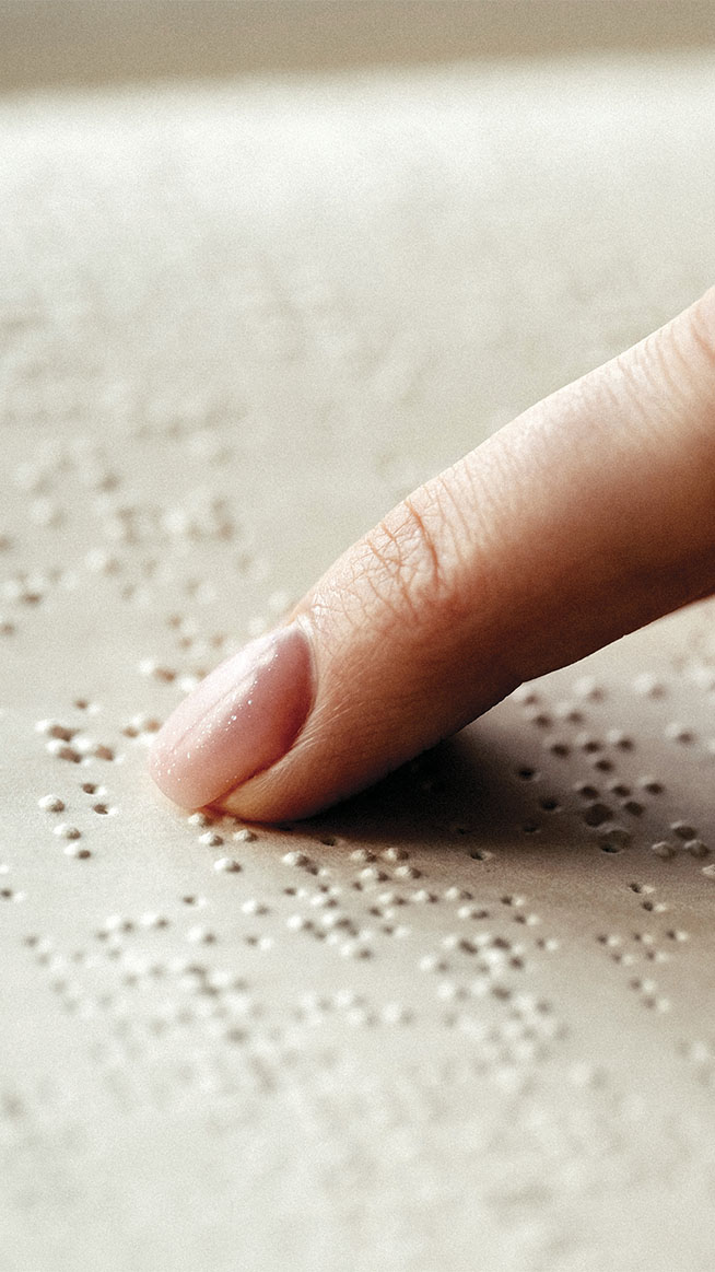 Dedo índice de mujer sobre papel con sistema braille