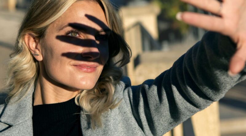 Mujer joven protegiendo sus ojos del sol usando su mano