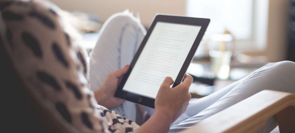 Persona sentada en una silla leyendo un texto en una tableta electrónica