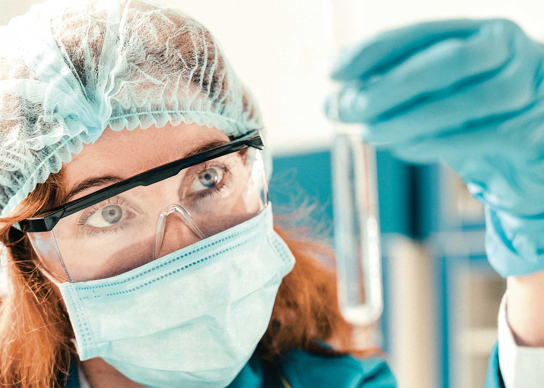 Mujer usando uniforme quirúrgico sosteniendo y observando un tubo de ensayo de laboratorio