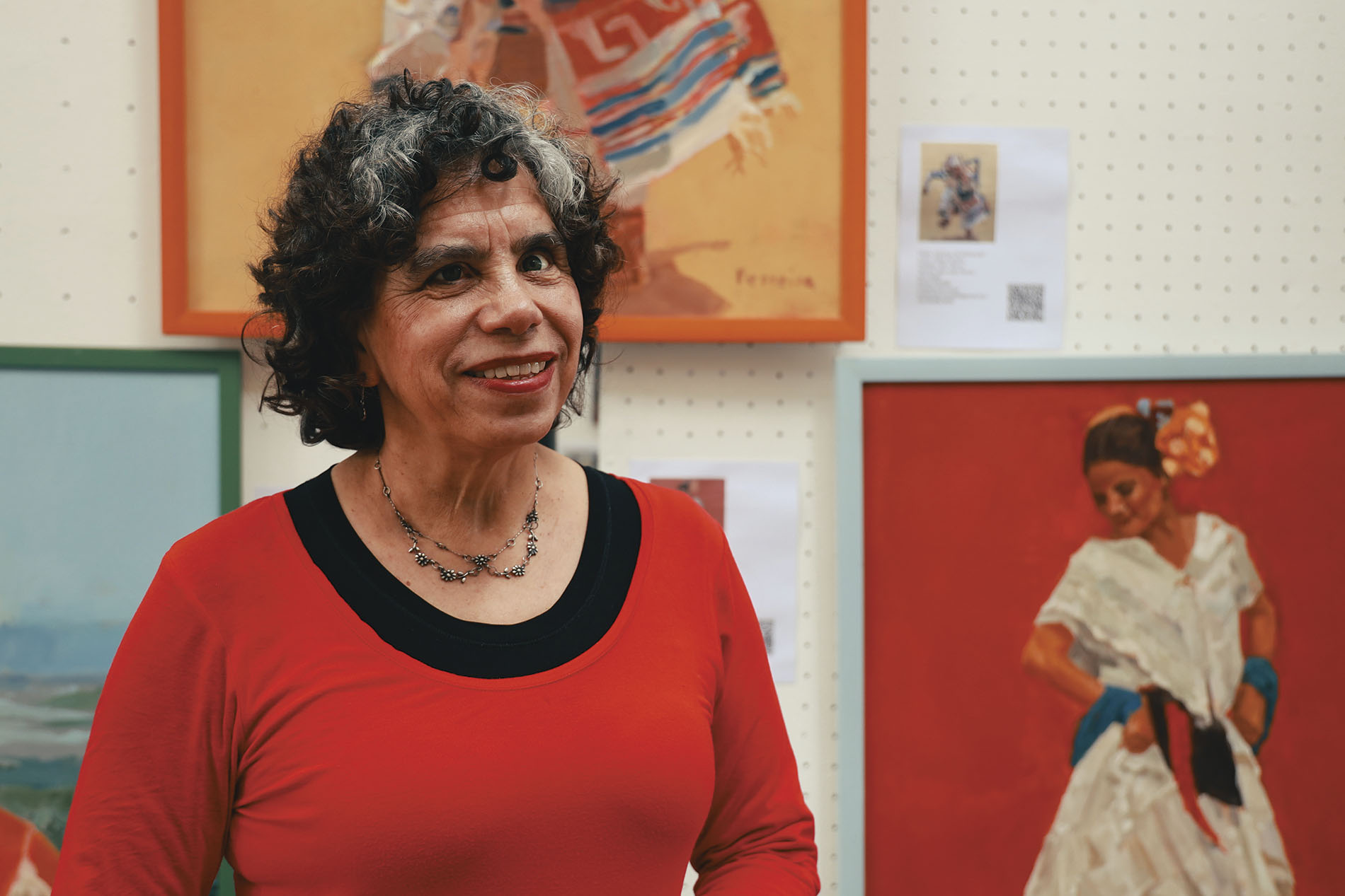 mujer con poca visión posando ante la cámara con obras de arte detrás de ella