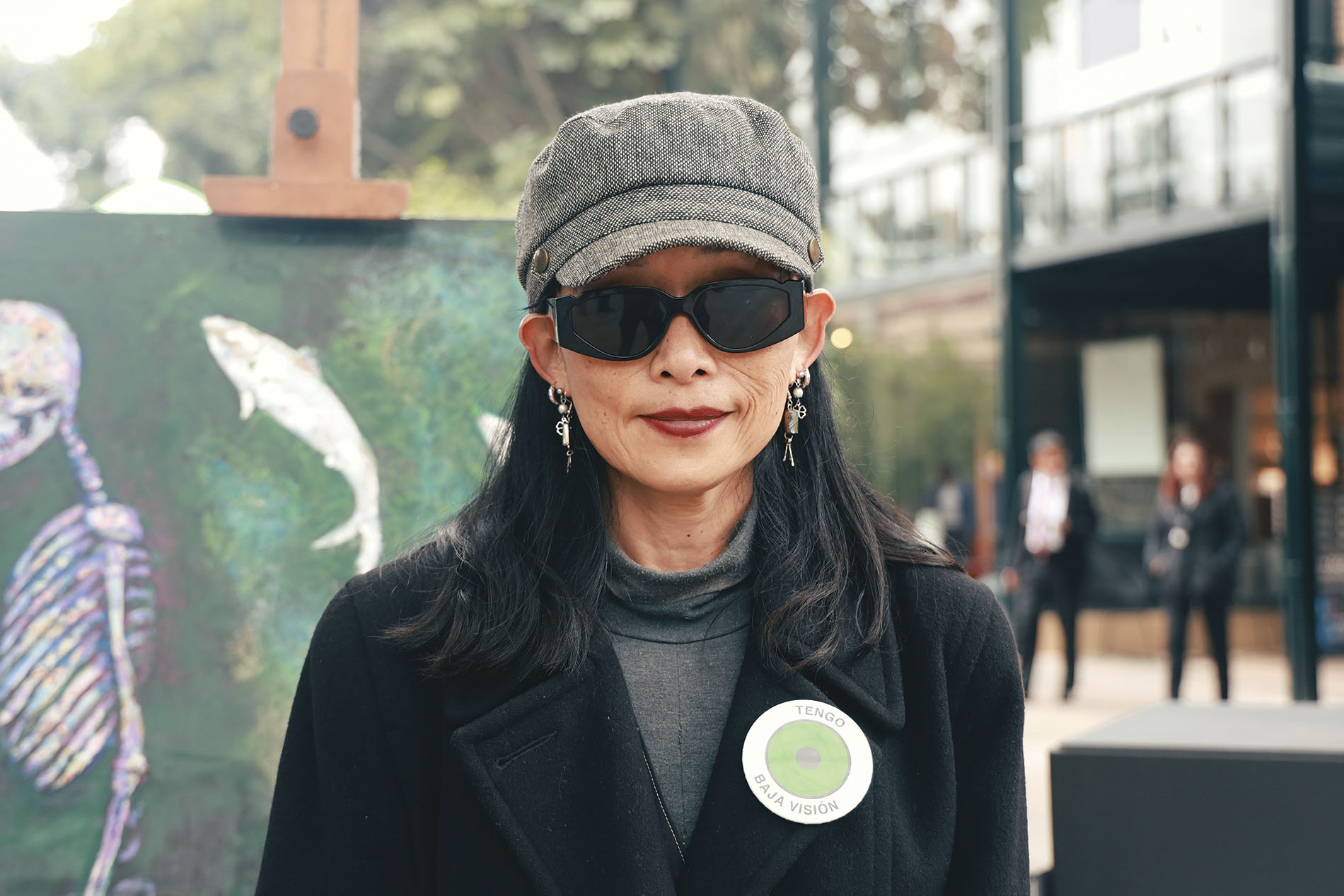 mujer con baja visión usando lentes oscuros sonriendo ante la cámara