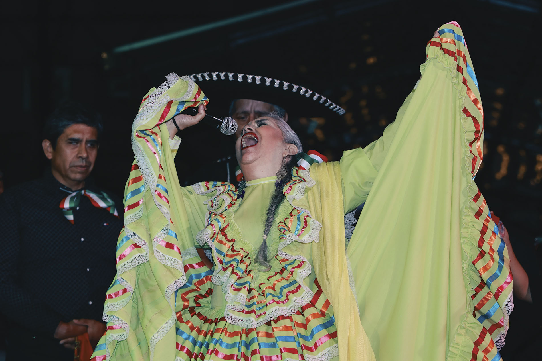 mujer con traje folclórico mexicano cantando con micrófono
