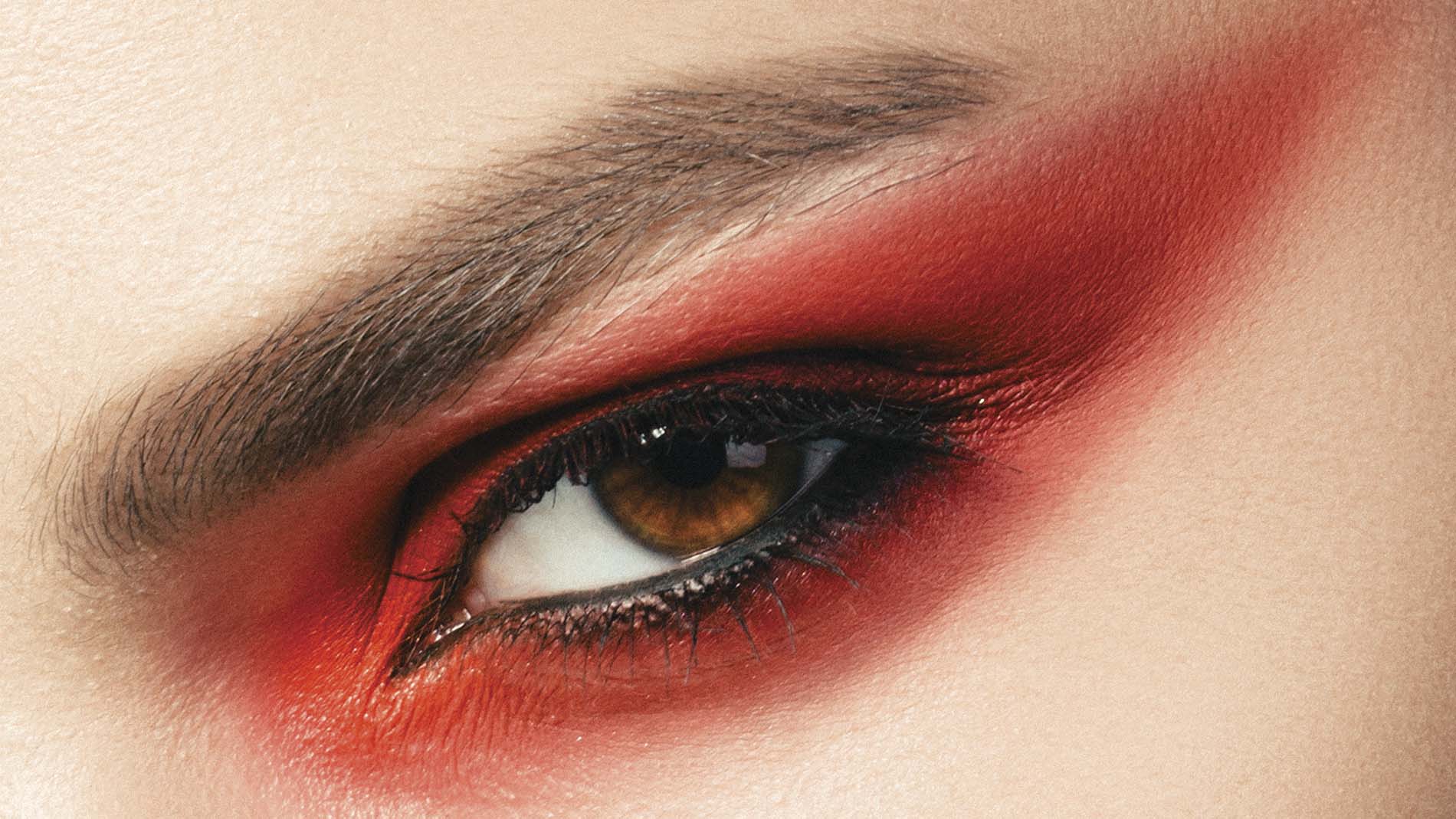 ojo de mujer con cosmético rojo en el párpado y delineador negro