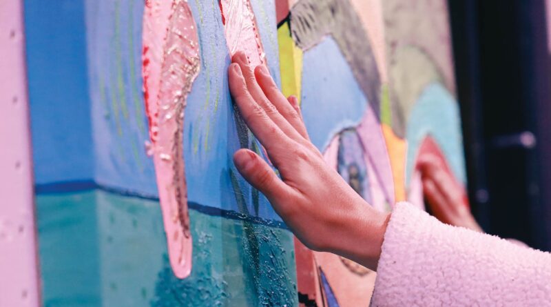 Mano de mujer tocando una obra de arte de color rosa, azul y verde