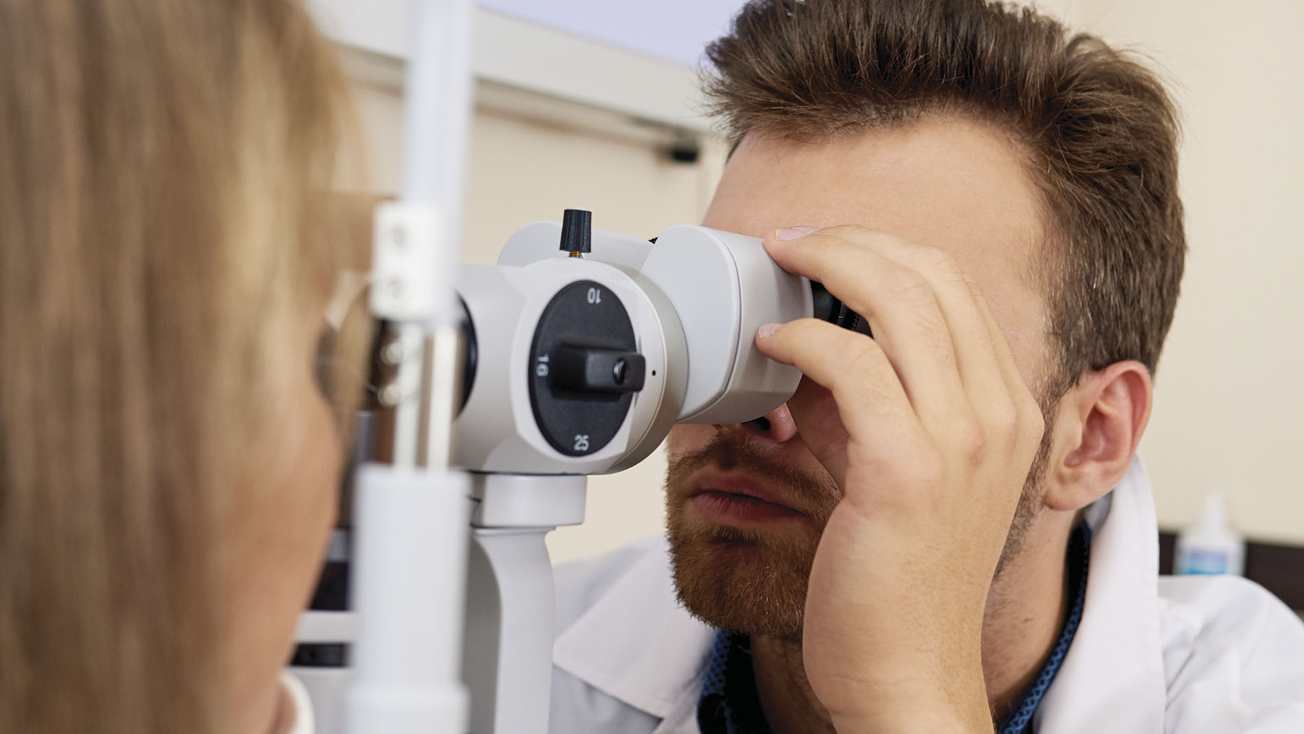 Foto de hombre joven realizando estudio de oftalmología con equipo médico