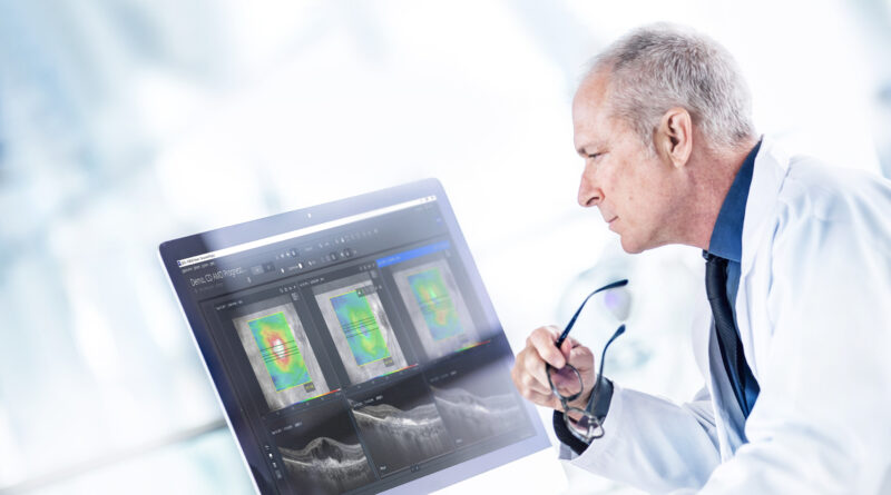 Médico en bata blanca observa atentamente imágenes clínicas de retina en una pantalla de computadora, que incluyen escaneos OCT y mapas de densidad visual, en un entorno moderno y luminoso.