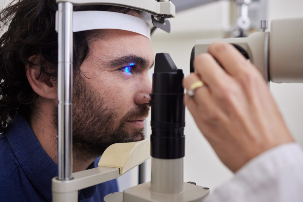 Paciente durante un examen oftalmológico con luz azul en lámpara de hendidura, parte del proceso de evaluación para glaucoma o presión intraocular.