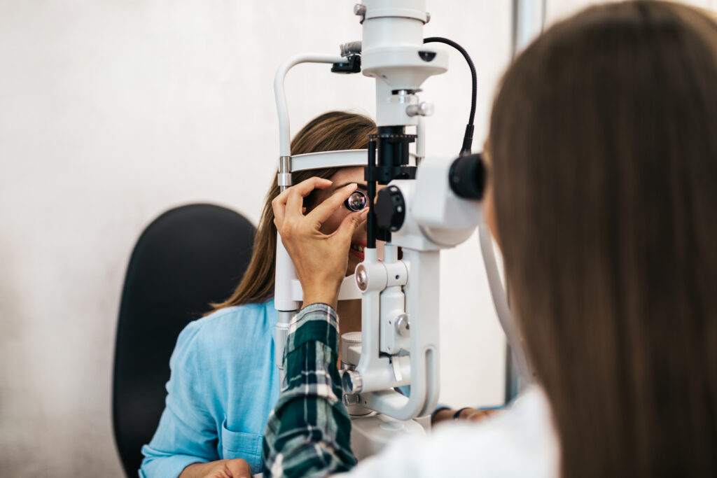 Optometrista realiza una revisión detallada con lente especial y lámpara de hendidura para evaluar la salud ocular de una paciente.