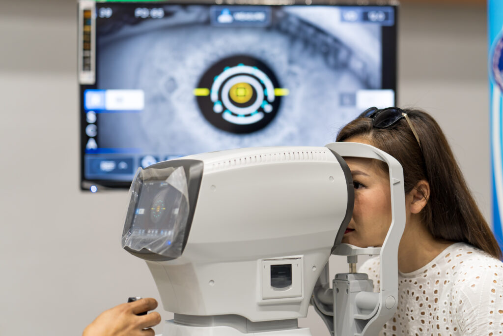 Mujer recibiendo un examen oftalmológico con equipo automatizado, mientras en el monitor se proyecta una imagen ampliada del ojo. Representa el uso de inteligencia artificial en la detección de enfermedades visuales como glaucoma y retinopatía diabética.