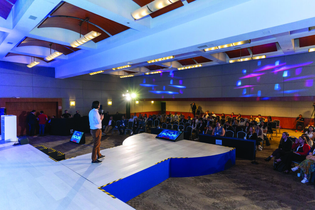 Escenario principal del evento de médicos oftalmólogos Oftafellow 2023. Se observa a un hombre joven hablando por micrófono ante el público que asisitió al evento